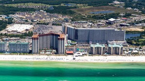 A coastal cityscape with a prominent hotel featuring multiple high-rise buildings, a beachfront, and a large body of water. - Shores of Panama 816 (Panama City Beach)