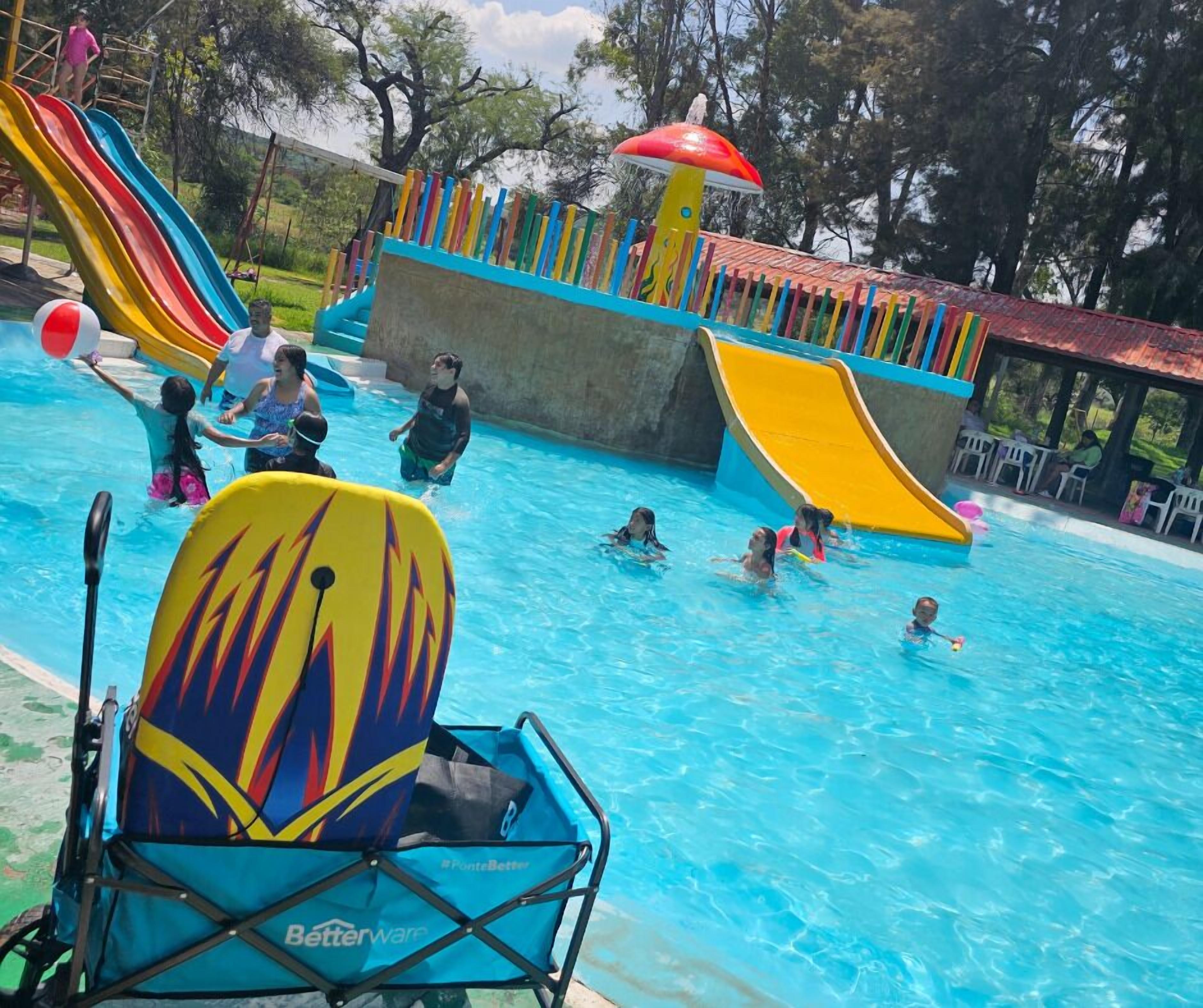 A swimming pool with multiple slides and a colorful play structure.