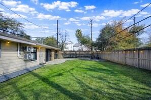 Une cour arrière avec une clôture en bois, une maison et un ciel dégagé.