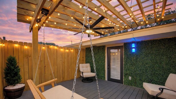 A wooden deck with a swing chair, a cushioned bench, and a small potted plant. - Charming 1-Bedroom Guest House Near NRG with a Level 2 Fast EV Charger (Houston)