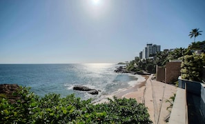 Vista costera con cielo despejado, una playa arenosa y un litoral rocoso.