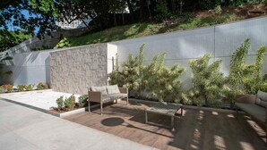 Un espace patio agrémenté d’un mur en pierre, d’un canapé en osier, d’une table en métal et de plantes en pot.