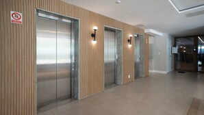 Un espace moderne avec ascenseurs, comprenant trois ascenseurs, des panneaux de bois sur les murs et un sol carrelé.