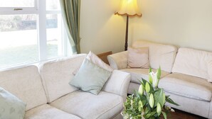 Ein Wohnzimmer mit einer Couch, einer Lampe und einem Fenster mit Vorhängen.