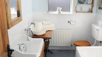 Une salle de bain avec un lavabo blanc, un meuble-lavabo en bois, des toilettes et une fenêtre donnant sur un beau paysage.