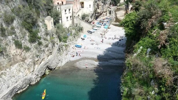 Una zona costera con un canal estrecho, una playa con barcos y edificios a lo largo de la costa.