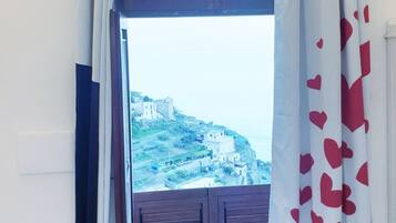 Una stanza con vista su una località costiera, una porta di legno e un letto.