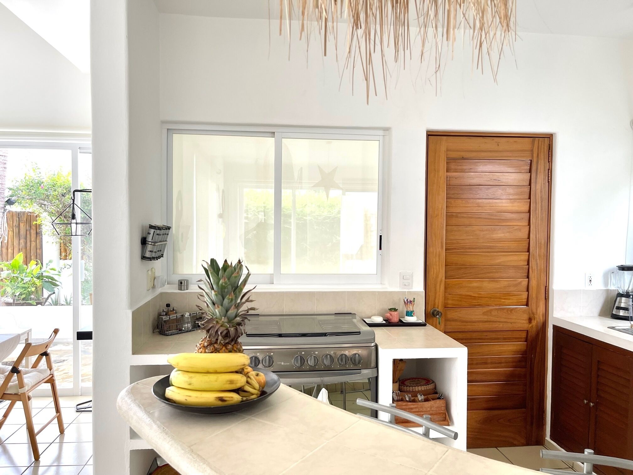 Une cuisine moderne avec une grande fenêtre, un fourneau et une porte en bois.