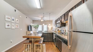Eine moderne Küche mit Holzboden, Edelstahlgeräten und Pendelleuchten.