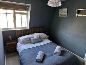 Une chambre à coucher avec un lit, une fenêtre, une table de chevet et une étagère fixée au mur.
