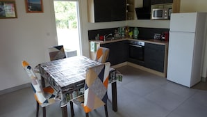 Eine kleine Küche mit Esstisch, Stühlen und einem Kühlschrank.