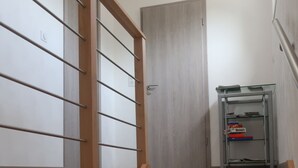 Eine Holztreppe mit Metallgeländer, das zu einer Tür führt.