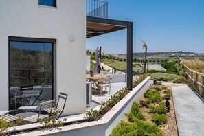 A modern building with a balcony, outdoor seating, and a view of the landscape. - Ocean Breeze Retreat - Near Ericeira by Lisbeyond (Carvoeira)