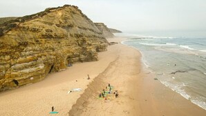 A beach with a rocky cliff and a sandy shore.