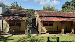 Two single-story buildings with red-tiled roofs, a grassy yard, and a small garden area.