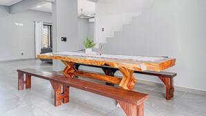 A spacious room with a large wooden table and benches, a potted plant, and a staircase.