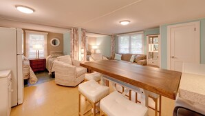 Un espacio habitable compacto con kitchenette, un comedor con mesa de madera y una sala de estar con sofá y sillones.