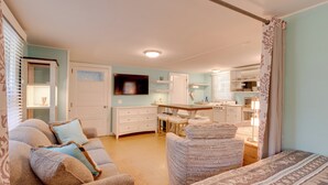 Una sala de estar acogedora con sofá, sillón y comedor con mesa y sillas.