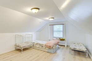 Een knus, goed verlichte slaapkamer op zolder met twee stapelbedden, een raam met jaloezieën en een radiator.