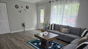 A living room with a grey sofa, a wooden coffee table, and a patterned rug.