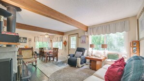 A cozy living room with a fireplace, a sofa, a chair, and a dining area. - Indoor Pool Access: Cabin in Lakes of the North! (Elmira)
