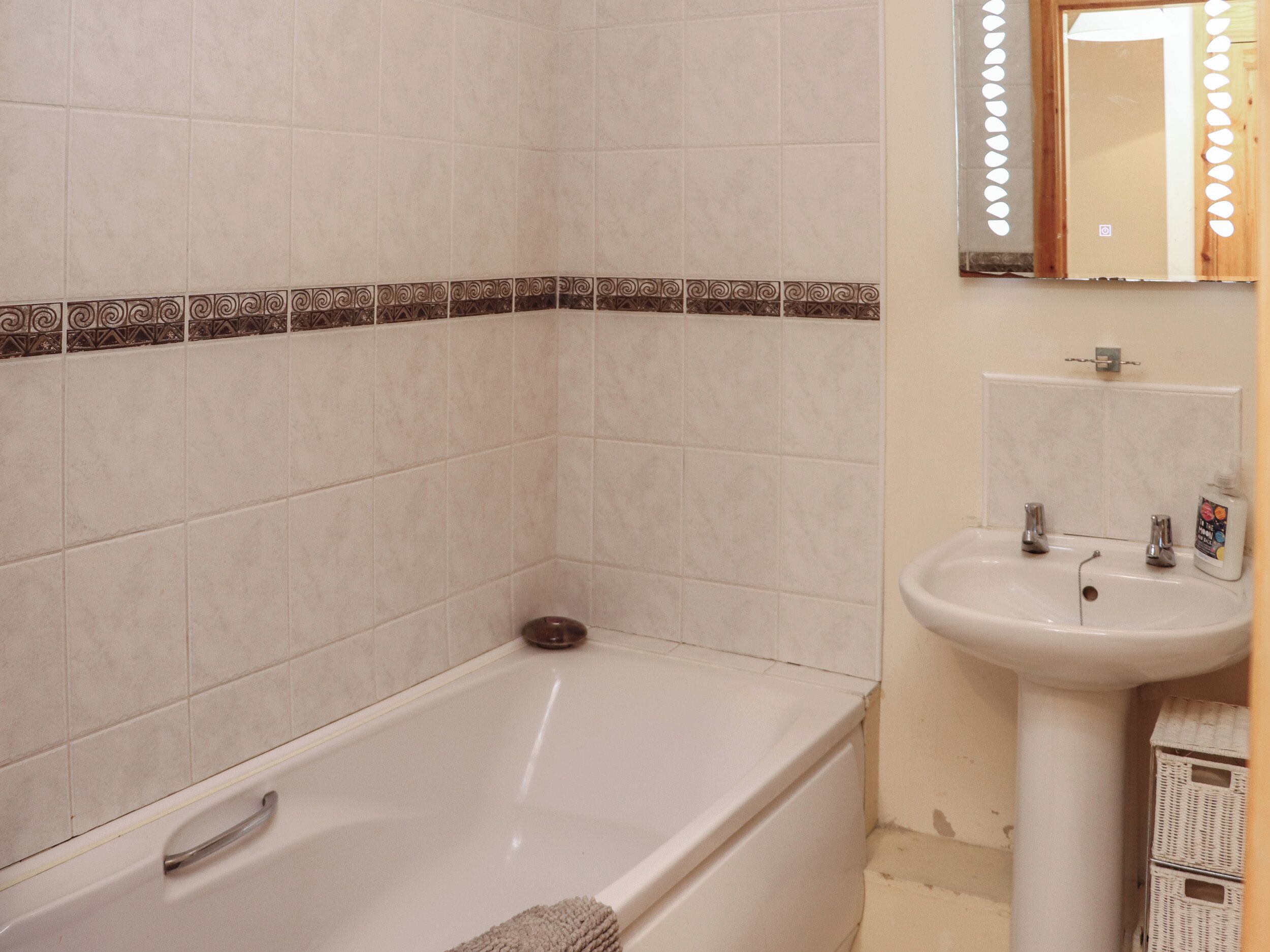 Un bany amb banyera, un lavabo i un mirall.