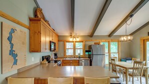Una cocina amplia con armarios de madera, una isla grande con taburetes de bar y un comedor con sillas de madera.