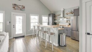 A modern kitchen with a central island, bar stools, and a stainless steel refrigerator.
