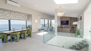 A modern living room with a dining area, large windows, and a view of the sea. - ATLANTIC SEA BREEZE, pet friendly in Gortahork, County Donegal (Falcarragh)