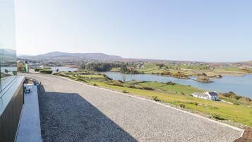 Vista desde una ventana sobre un paisaje rural con un lago, campos y colinas al lejano.
