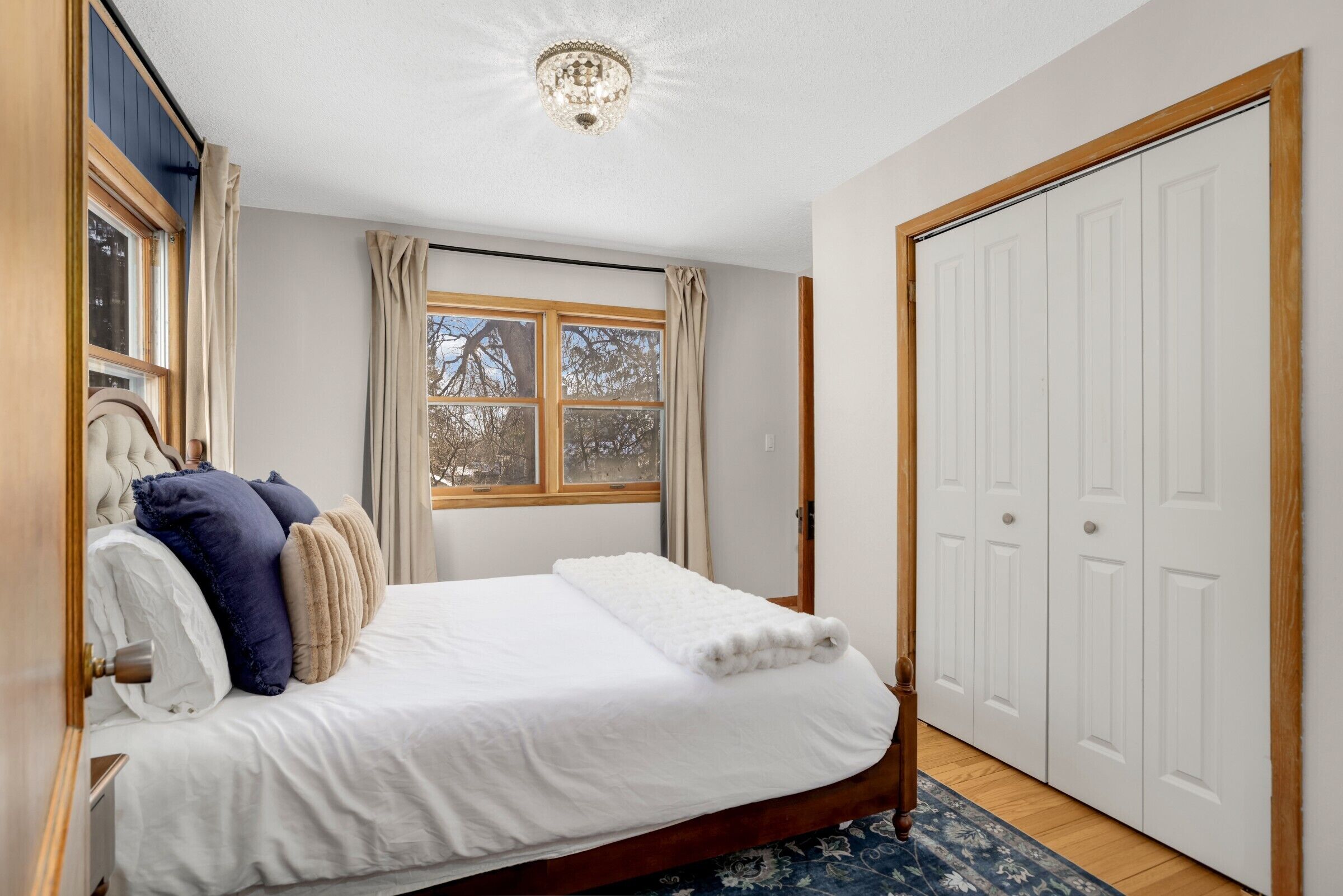 Une chambre à coucher avec un grand lit, une fenêtre avec des rideaux, une armoire et un lustre.