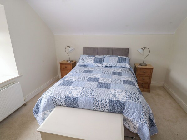 A bedroom with a bed, two nightstands, a bench, and a radiator.