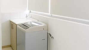Une salle de bain moderne et compacte, dotée d’un lave-linge encastré, d’un petit meuble et d’un miroir.