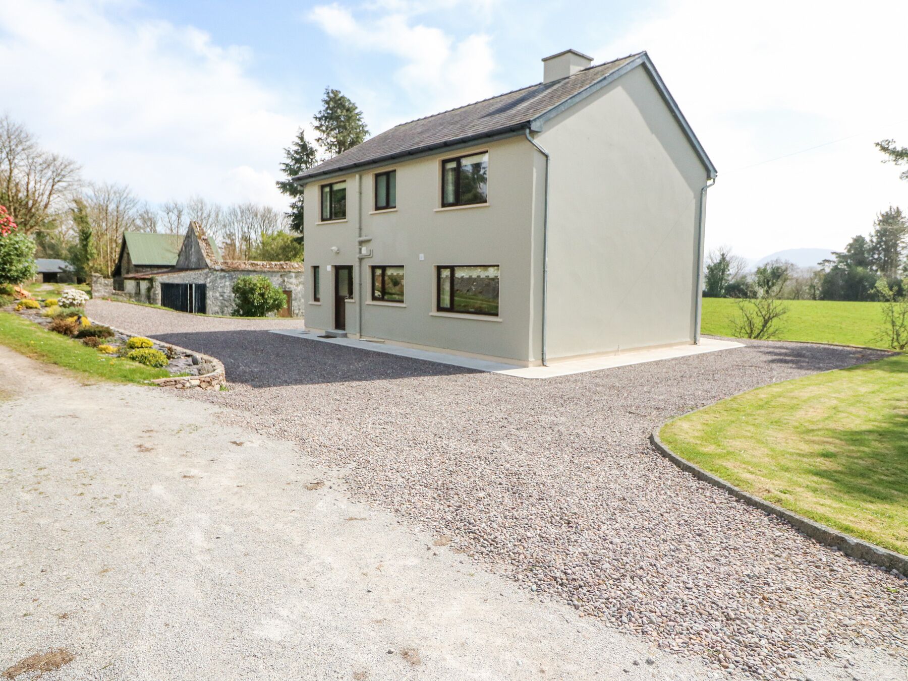 A modern two-story house with a gravel driveway and a well-maintained lawn.