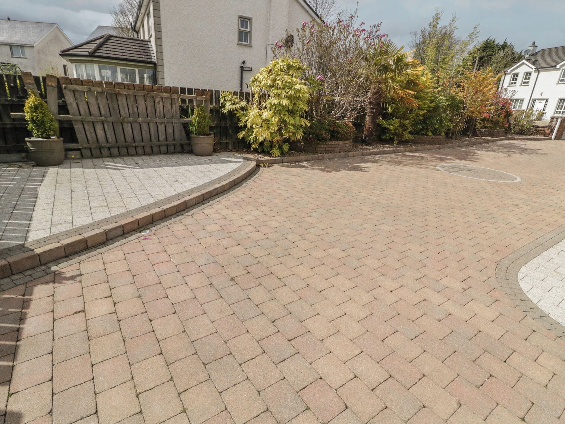 Un sendero pavimentado con cerca de madera y plantas en macetas.