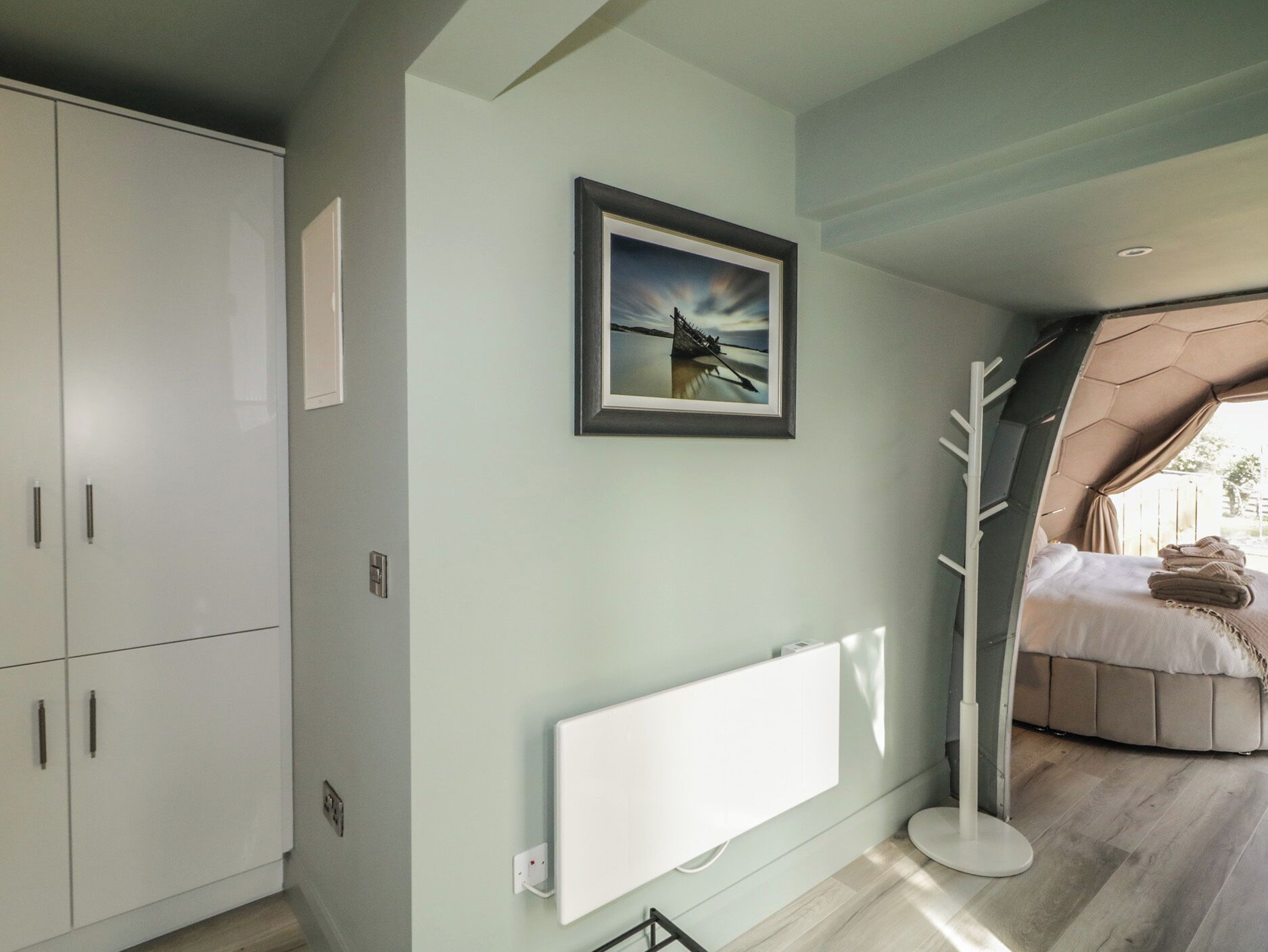 A bedroom with a bed, a radiator, and a picture on the wall.