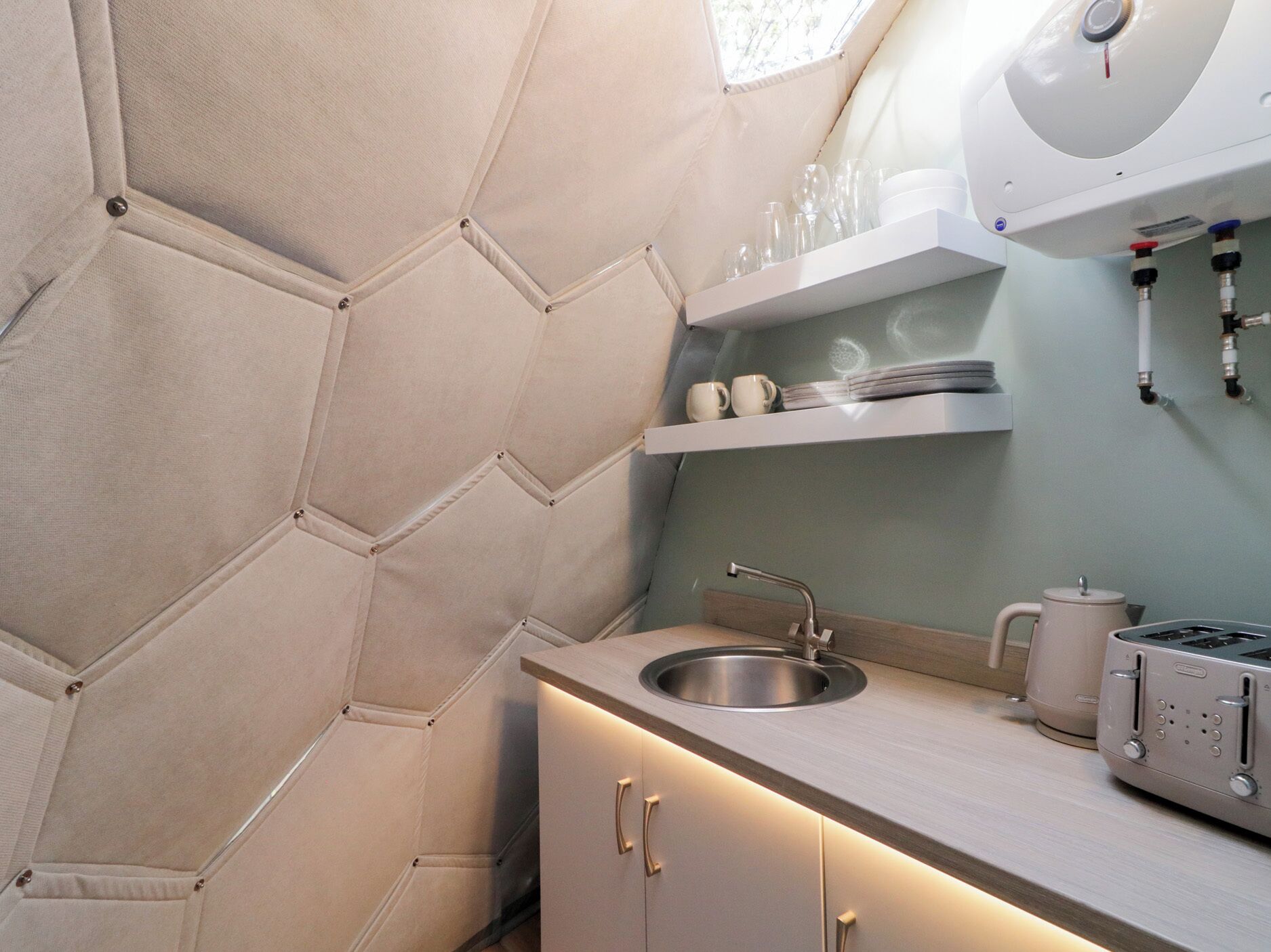 A compact kitchen with a built-in oven, a sink, and a coffee maker.