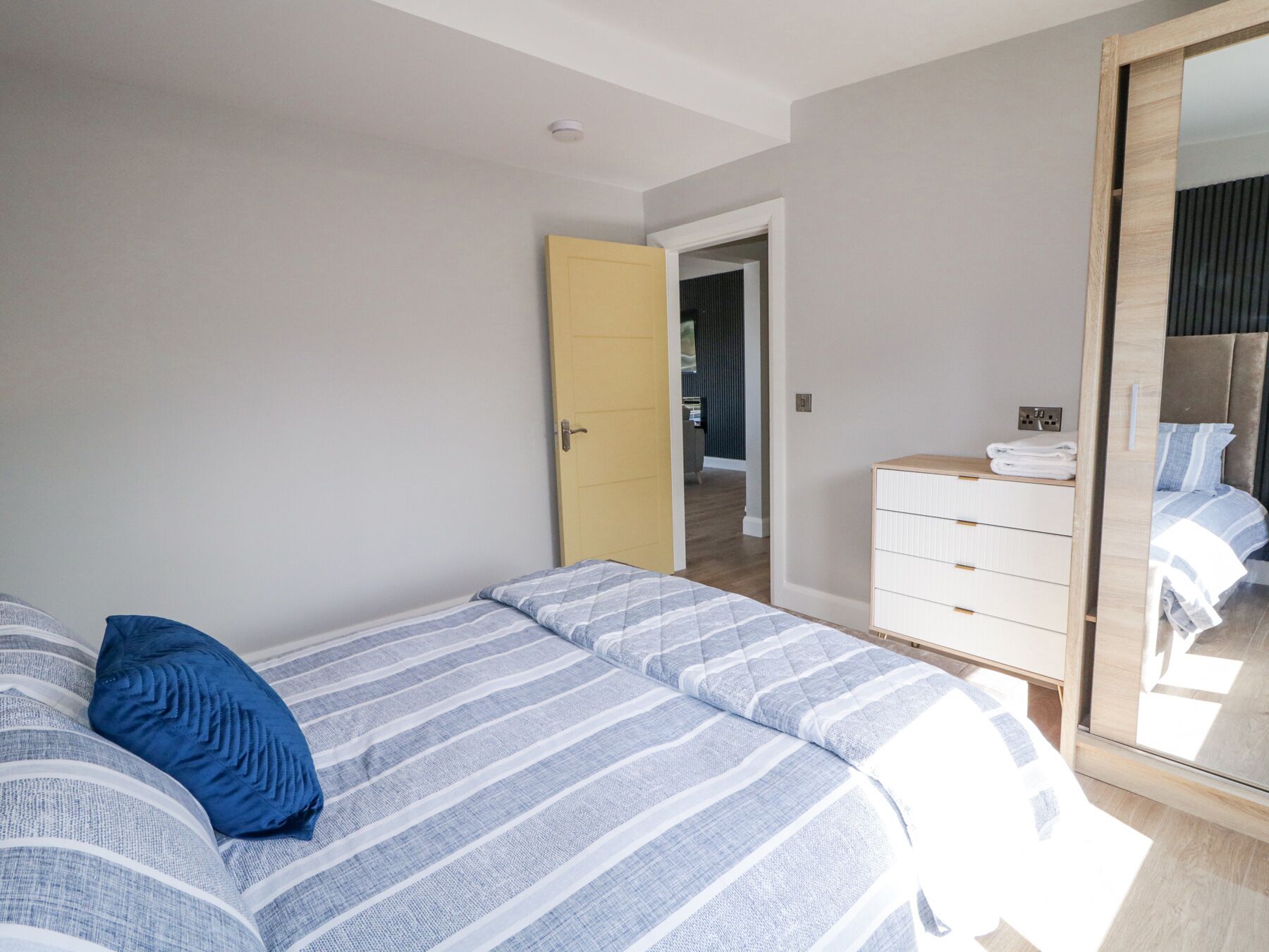 Een slaapkamer met een bed, een kast en een spiegel.