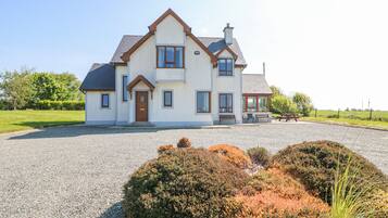 A two-story house with a gravel driveway and a well-maintained garden.