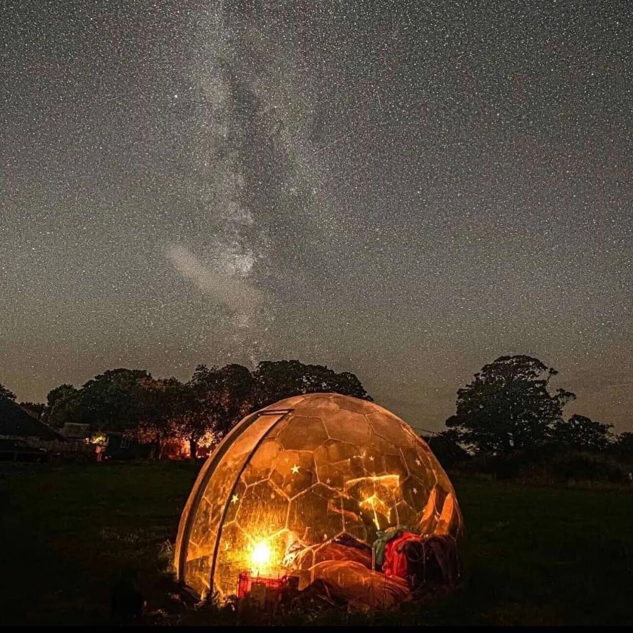 A geodesic dome structure with a fire inside, set against a starry night sky.
