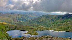 Vista panorámica de un paisaje montañoso con un lago y carreteras sinuosas.