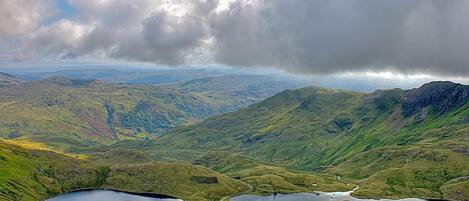 A panoramic view of a mountainous landscape with a lake and winding roads.
