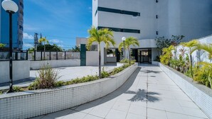 Een modern gebouw met een betegelde gevel, een verharde looppad en palmbomen.