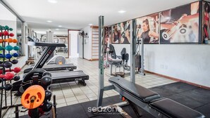 A gym with exercise equipment, a treadmill, and a bench. - Cozy Studio Near the sea in Salvador Mpa107 (Salvador)