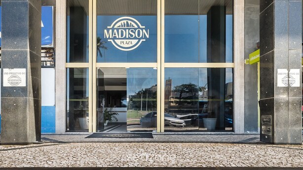 The entrance to Madison Plaza with a glass facade and a logo above the doors. - Cozy Studio Near the sea in Salvador Mpa107 (Salvador)