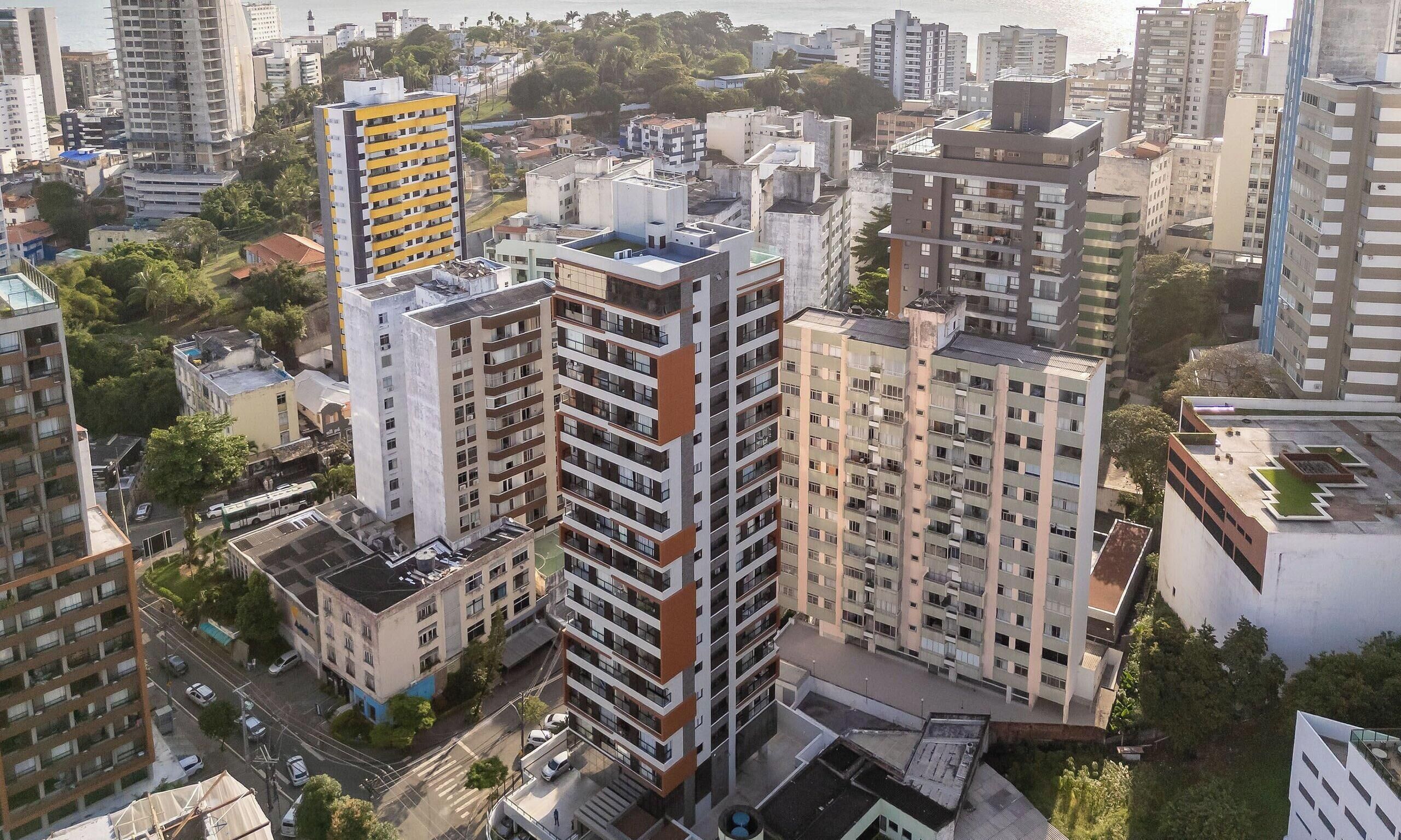 A high-rise building with multiple floors, surrounded by other buildings, and a street with vehicles.