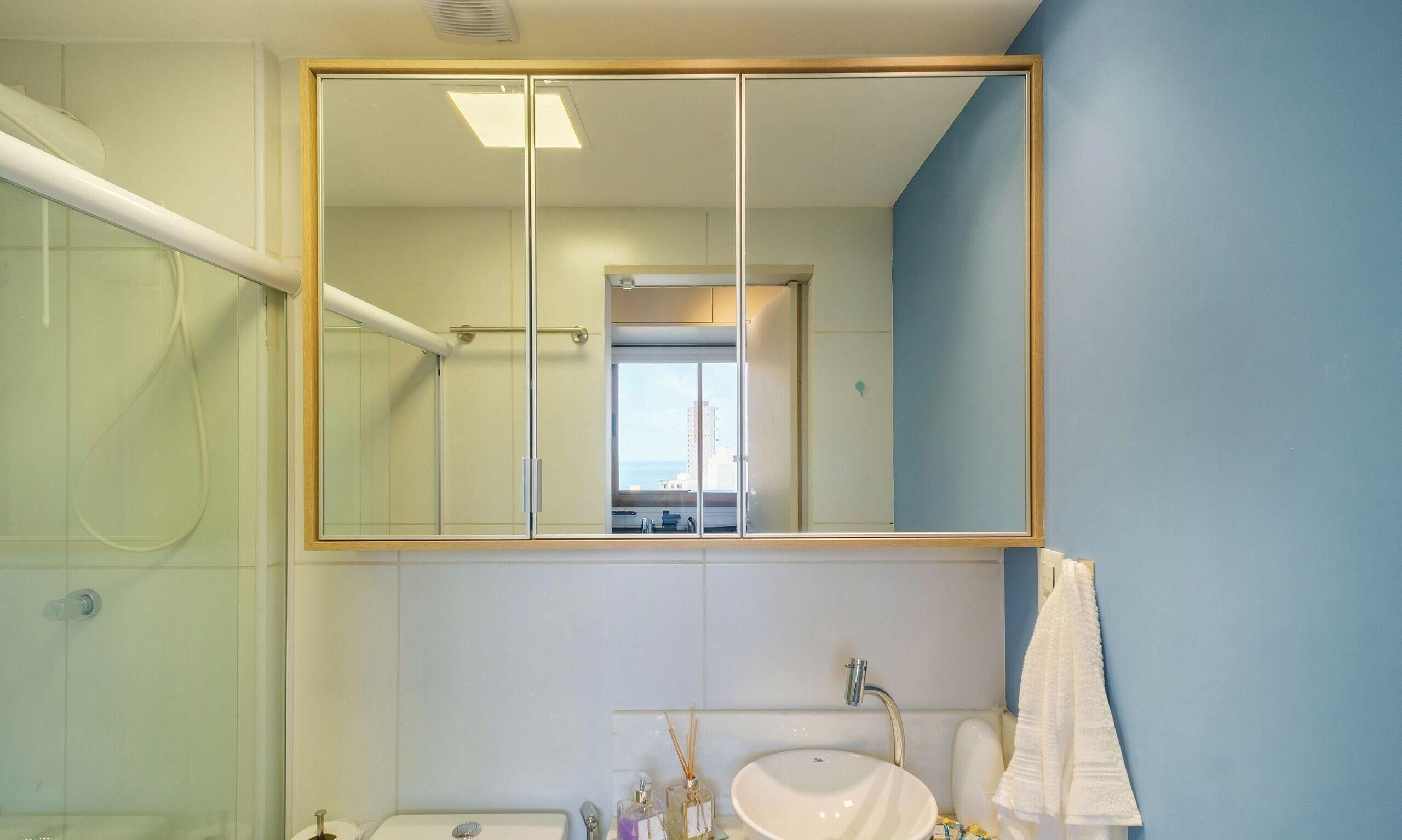Une salle de bain avec un grand miroir, un lavabo et un espace douche.