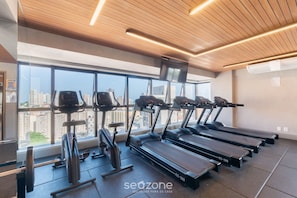 Una palestra con tapis roulant, cyclette e un'ampia vetrata con vista sulla città.
