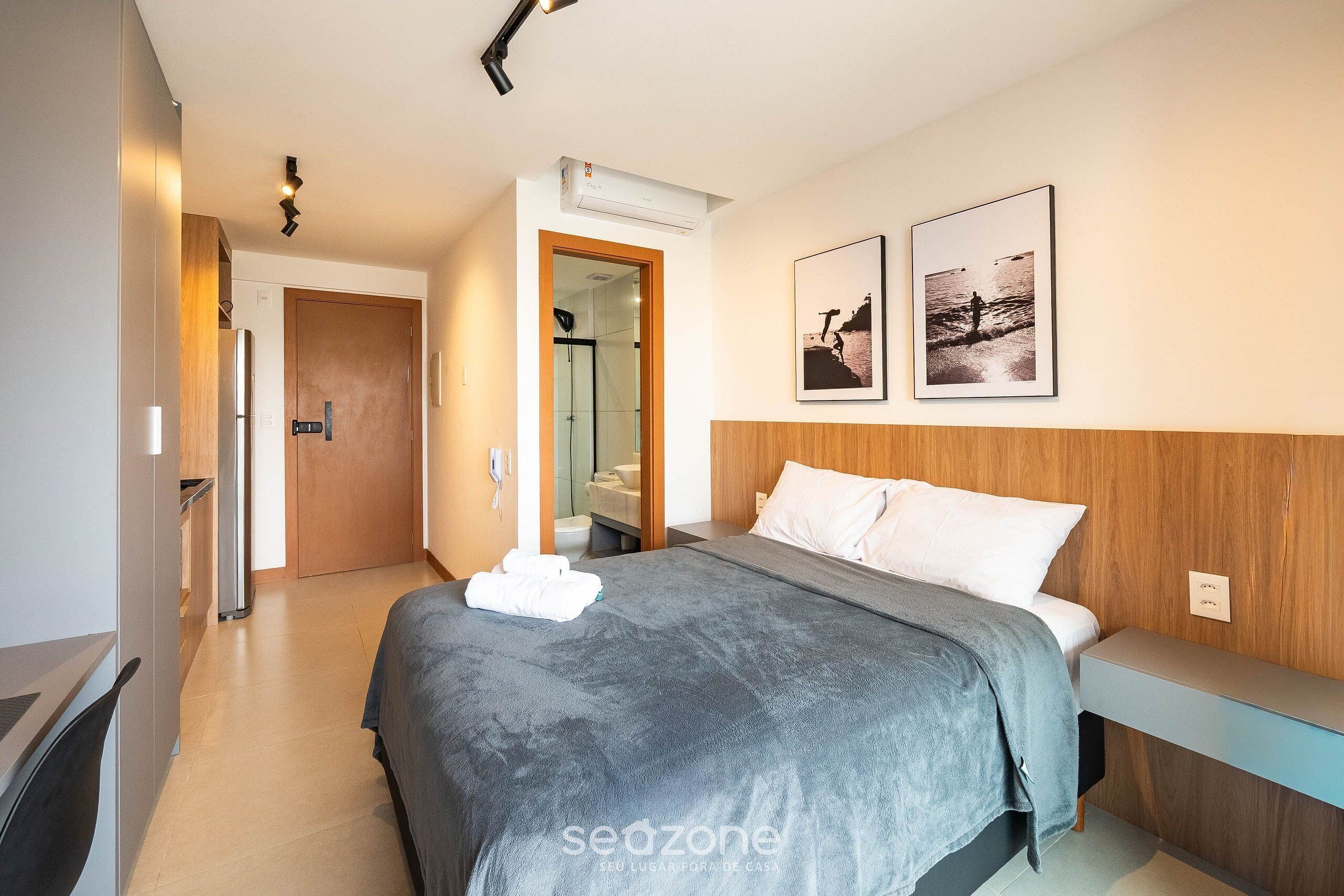 A modern hotel room with a bed, a desk, a shower, and a bathroom.