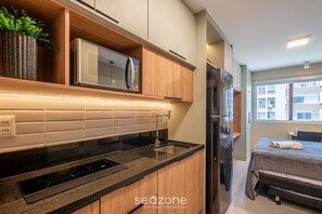 A modern kitchen with a built-in microwave, a stainless steel refrigerator, and a wooden cabinet. - Modern and Fully Equipped Apartments 500m From Barra Beach in Salvador ZBN (Salvador)